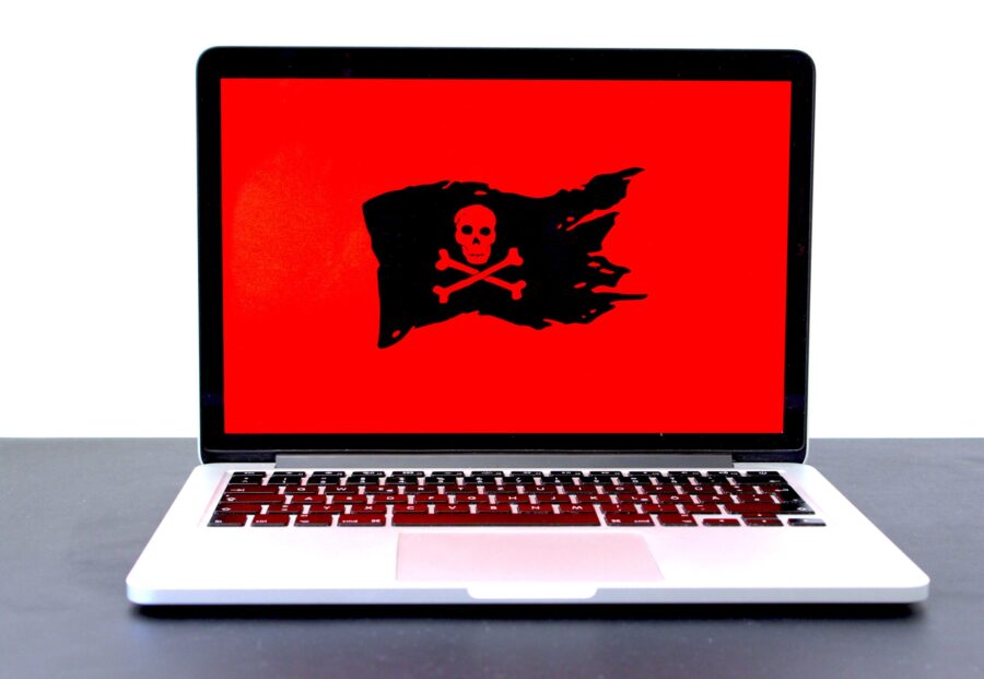 Laptop displaying a pirate flag / jolly roger on a red screen, possibly indicating malware, hackers or a different computer problem. If you like that image, consider donating at https://sharethemeal.org/donate - thanks!