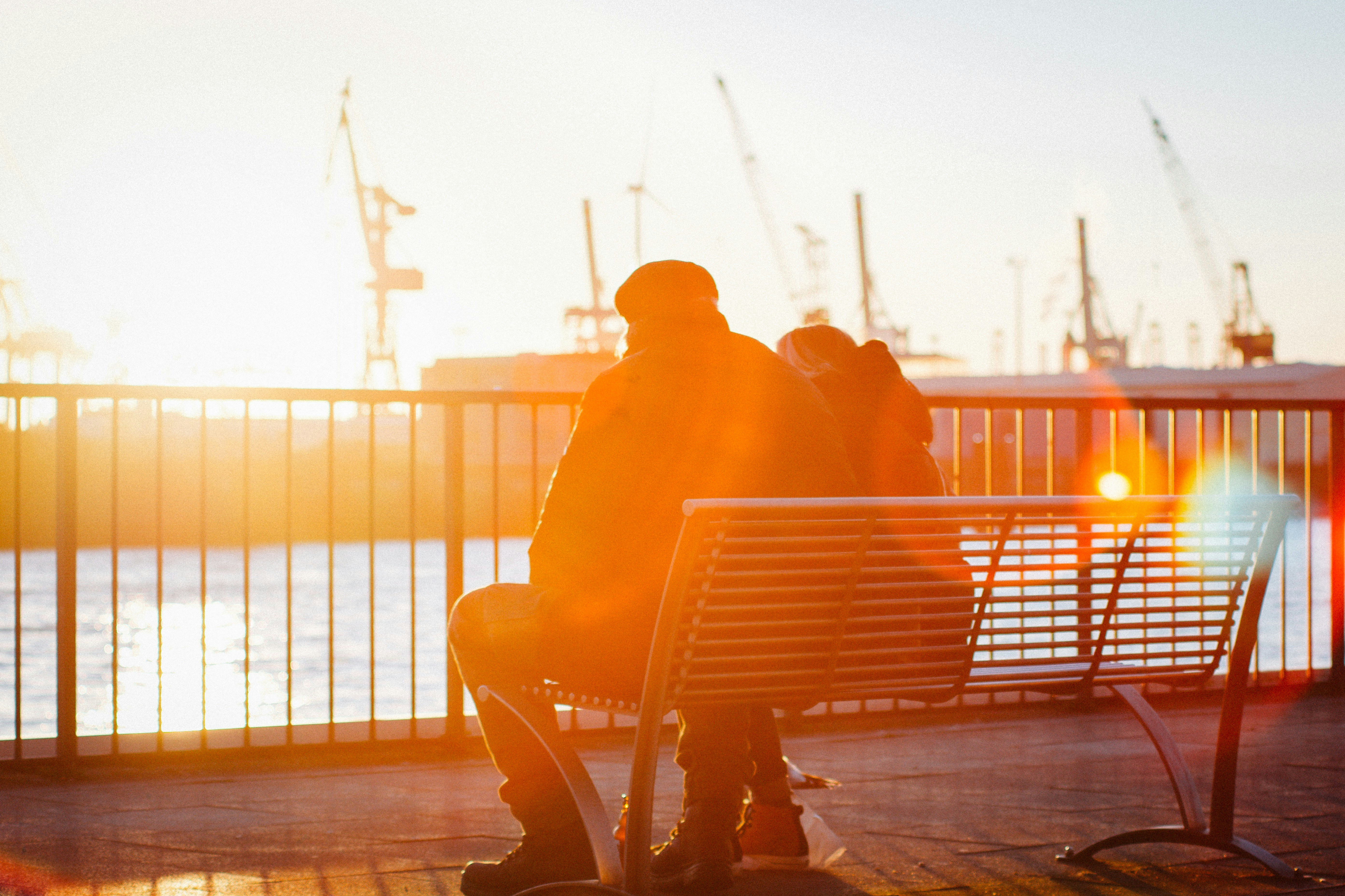 Two romantic seniors sitting at port of Hamburg, Germany during golden hour